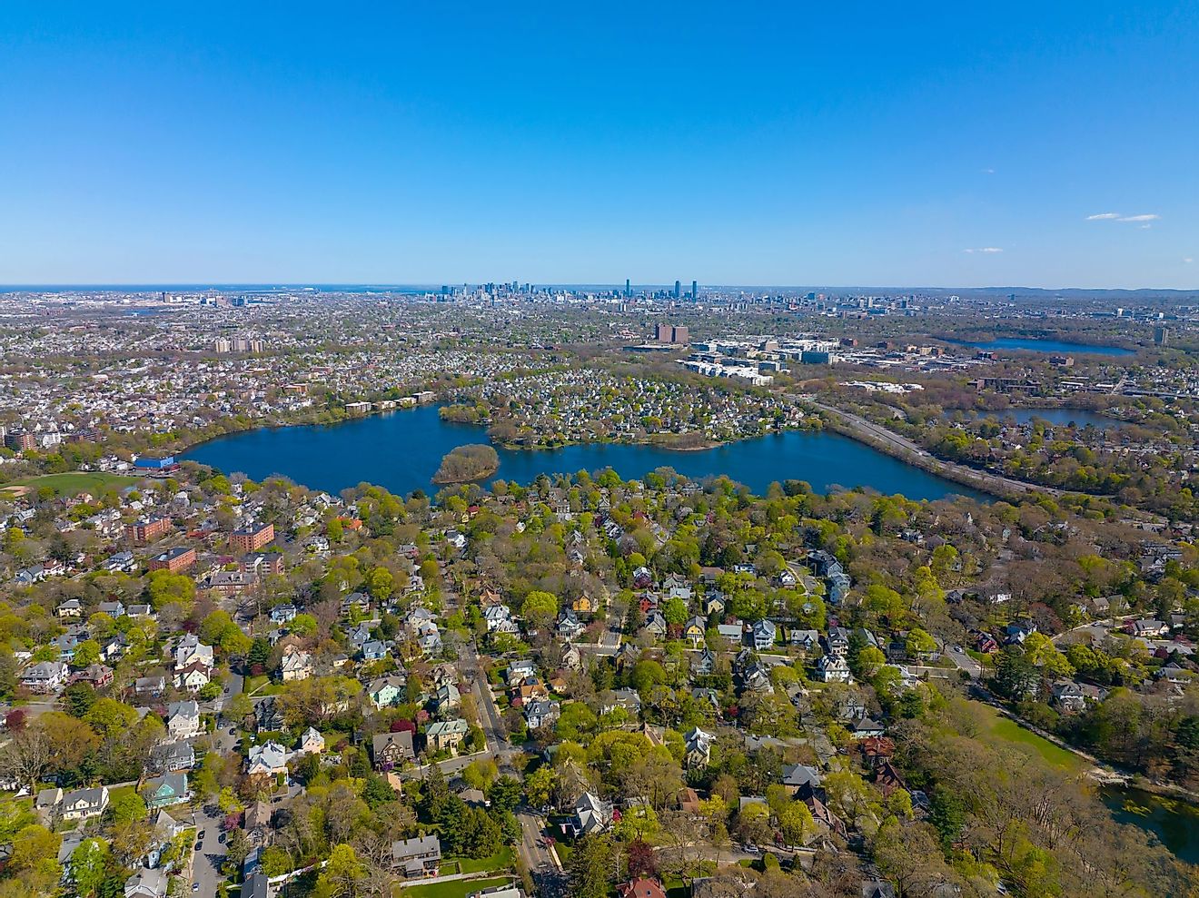 Aerial view of Arlington Heights suburban landscape in spring with Spy Pond and Boston modern city skyline at the background in the historic town of Arlington, Massachusetts