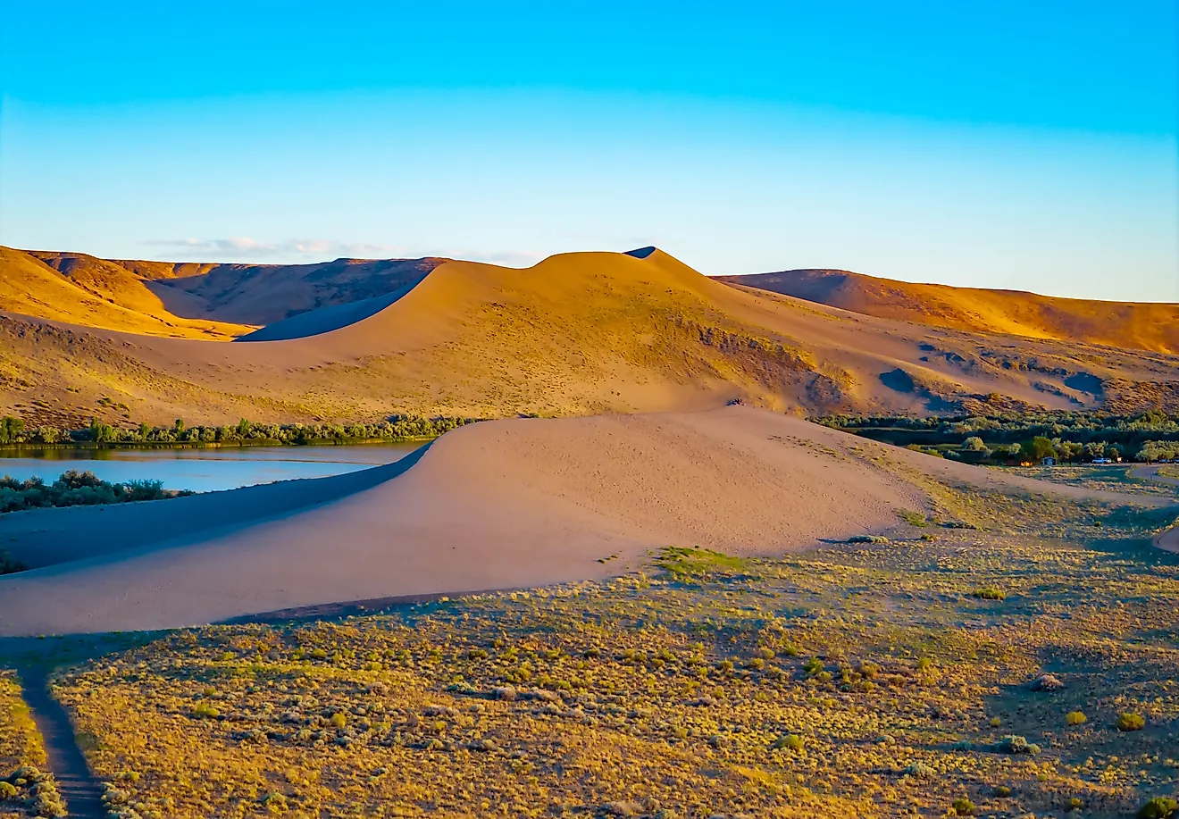 Vibrant golden sunset glow illuminates the towering sand dunes at Bruneau Dunes State Park. Credit: Photo Spirit/ Shutterstock.com