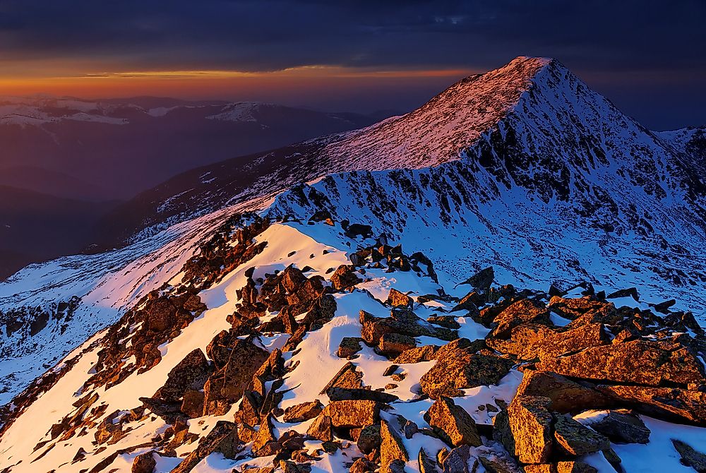 The sun sets over the majestic peaks of Retezat National Park in Romania. 