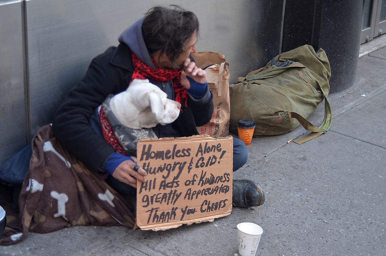 A homeless man sitting on the street with a dog and asking for help February 25, 2012 in New York City.