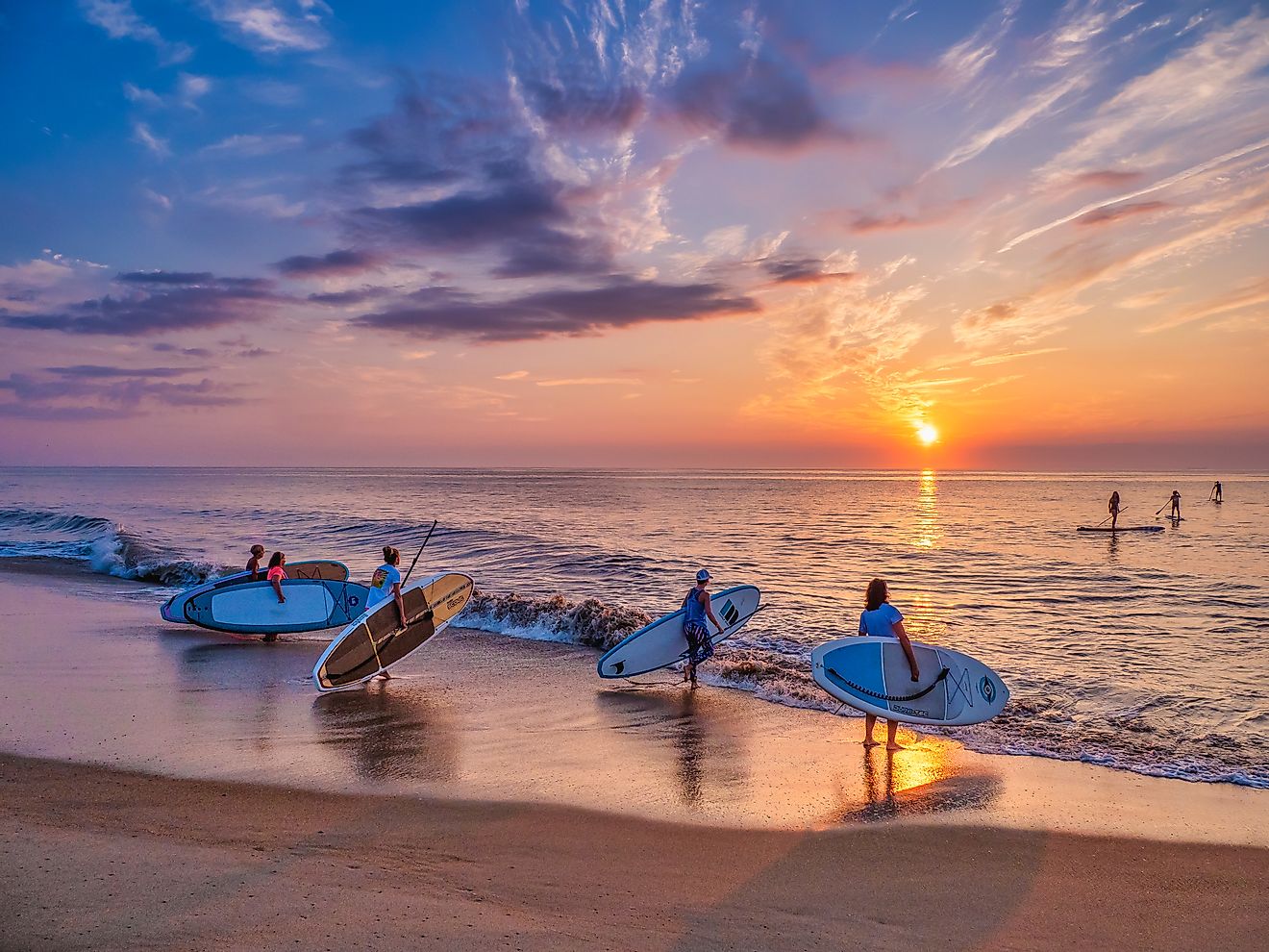 Group of young women paddleboarding at sunrise along the coast of Bethany Beach, Delaware, USA. Editorial credit: David Kay / Shutterstock.com