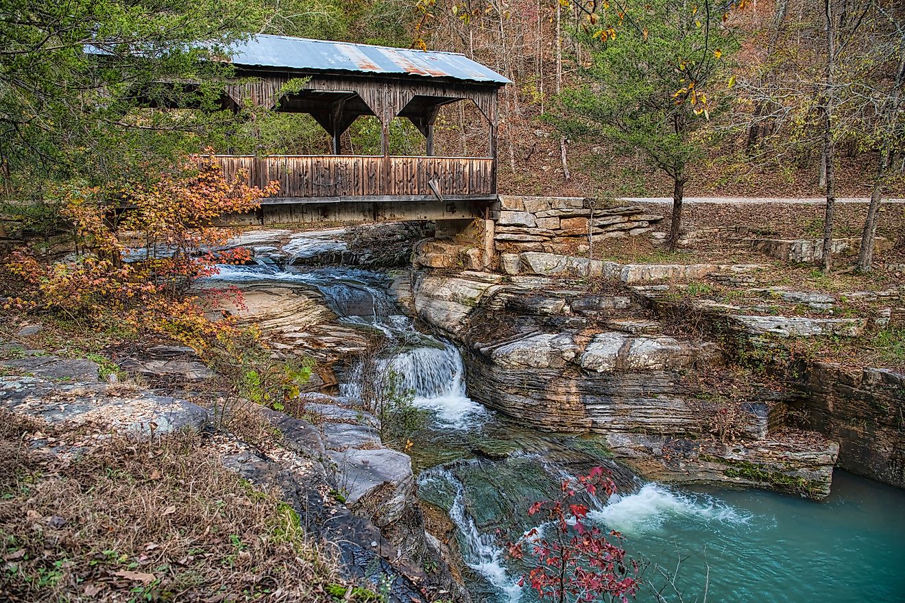 A quaint covered bridge over a cascading waterfall in Ponca, Arkansas.