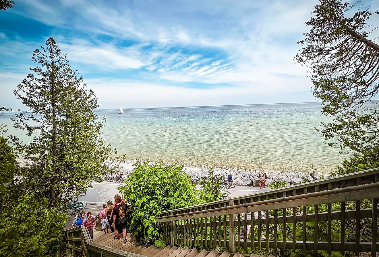 Wooden stairway leading through the forest to the Arch Rock natural limestone formation in Mackinac Island. Image credit: Sanya Kushak via Shutterstock.