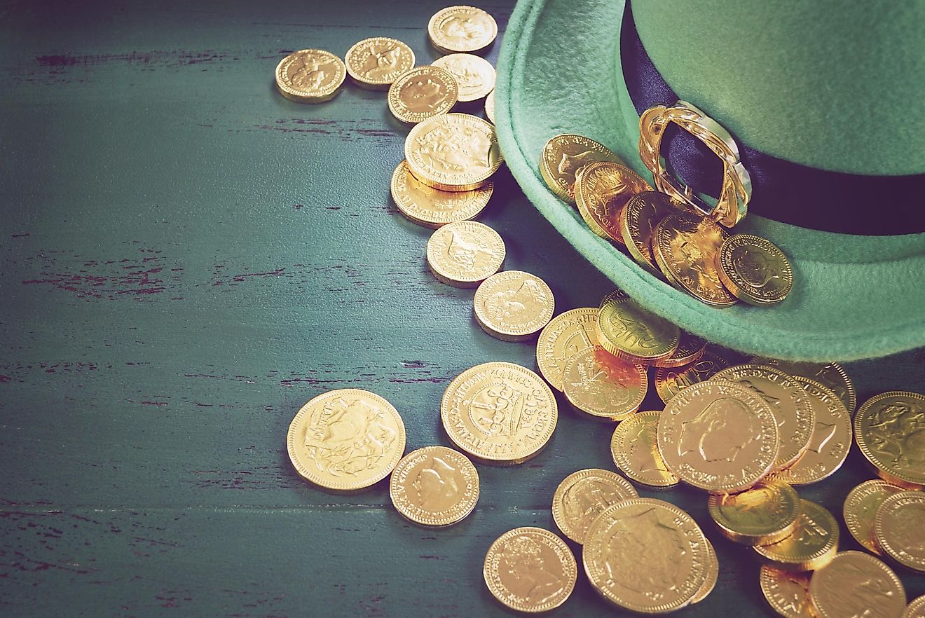 Happy St Patricks Day leprechaun hat with gold chocolate coins on vintage style green wood background, with retro vintage style filters.