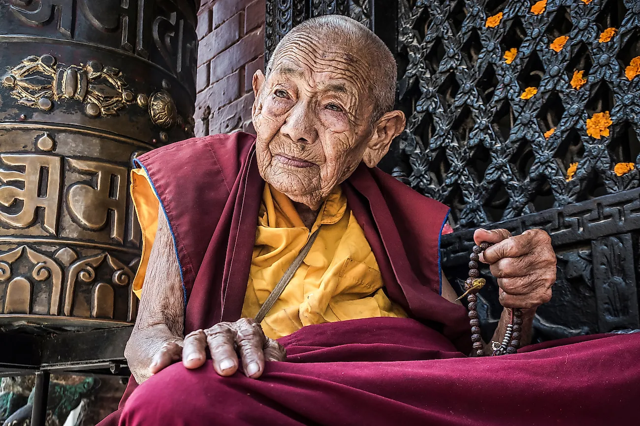 Portrait of an old Nepalese buddhist nun praying in front of Bodnath stupa, Kathmandu, Nepal. Image credit: Chris Piason/Shutterstock.com