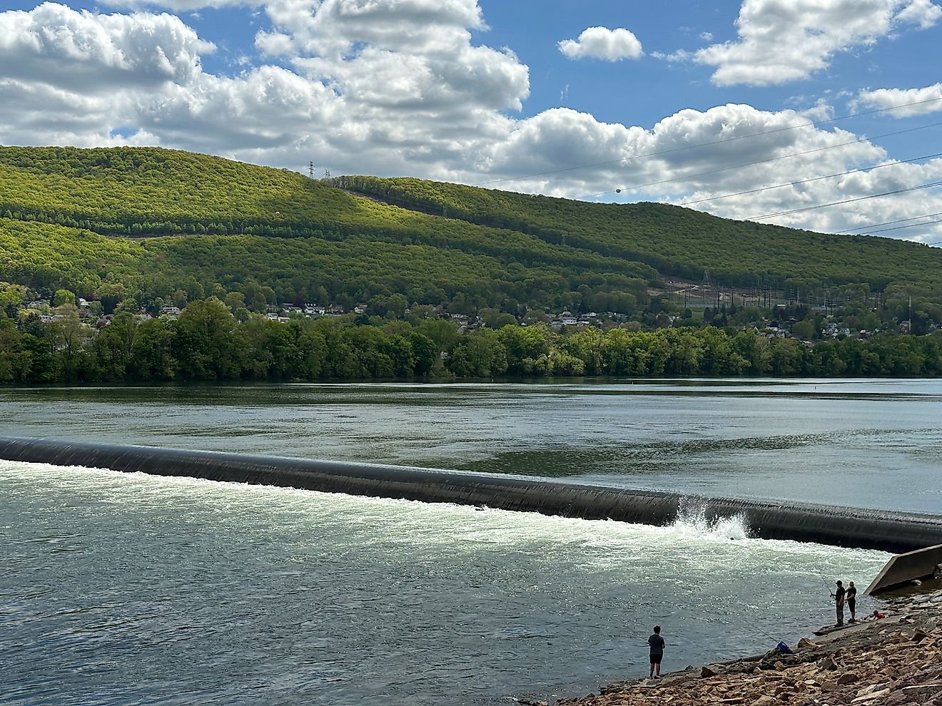 People on the bank fishing by the dam at the West Branch of the Susquehanna River in Williamsport, Pennsylvania.