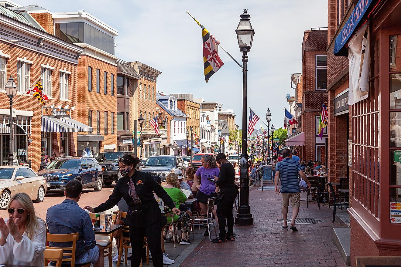 Street view of Annapolis, Maryland with people walking in historic town and people dining outdoor sitting on tables put on street by local restaurants.