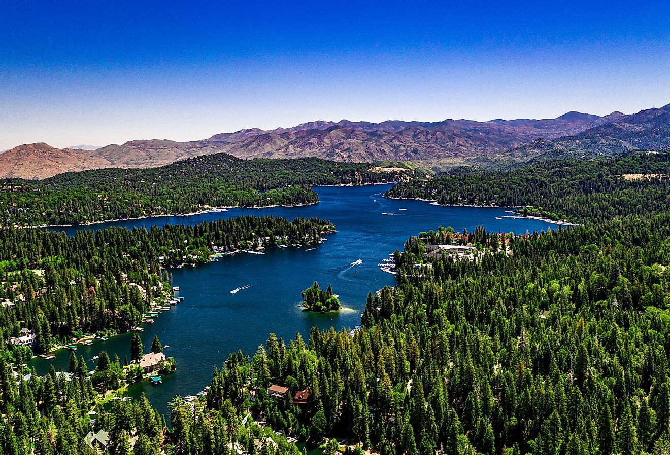 Aerial, drone panorama of Lake Arrowhead in the San Bernardino Mountains, California on a clear, summer day with blue water and sky, purple mountains and green trees