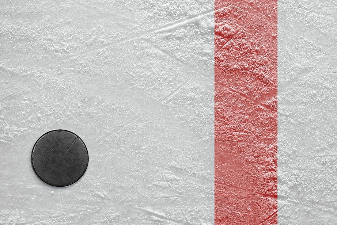 A puck is shown on a hockey ice rink in an arena. 