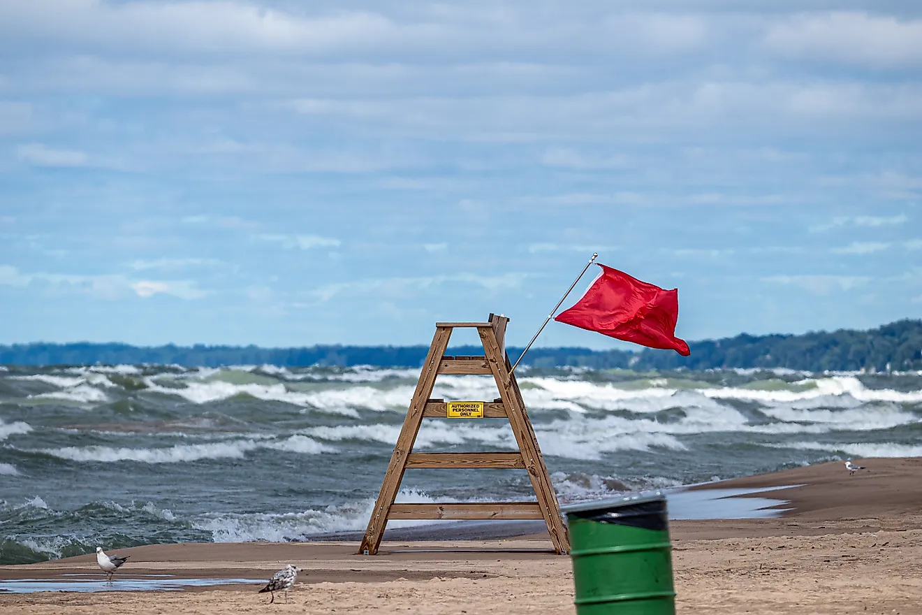 Red warning flag flying on a wooden lifeguard chair at Lake Michigan during hazardous water conditions