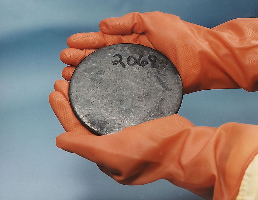 A billet of highly enriched uranium being held in gloved hands.