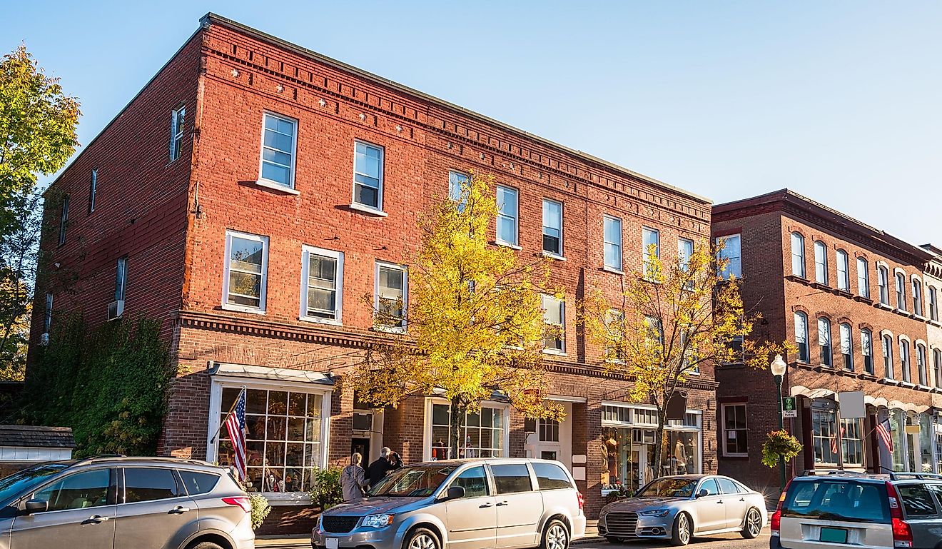 Traditional American brick buildings with shops along a busy street at sunset. Woodstock, VT, USA.