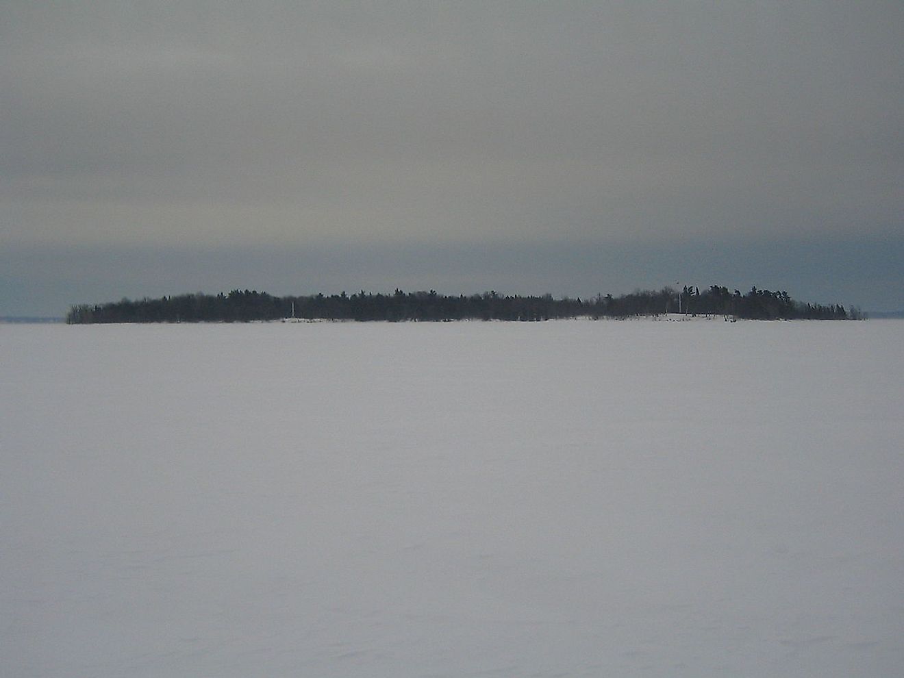 Crab Island as seen from the frozen ice of Lake Champlain in January 2009. The island's monument and flagpole can be seen in the enlargement to the left and right respectively. Image credit: M. Boire/Public domain