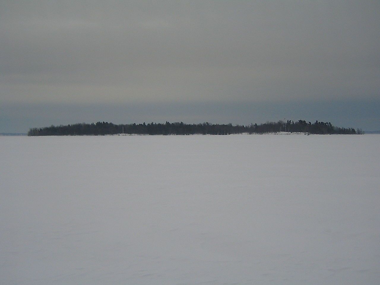 Crab Island as seen from the frozen ice of Lake Champlain in January 2009. The island's monument and flagpole can be seen in the enlargement to the left and right respectively. Image credit: M. Boire/Public domain