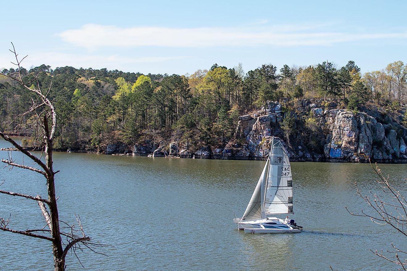 A sailboat floats past the rock formation known as Chimney Rock on Lake Martin on a sunny spring day. Editorial credit: JNix / Shutterstock.com