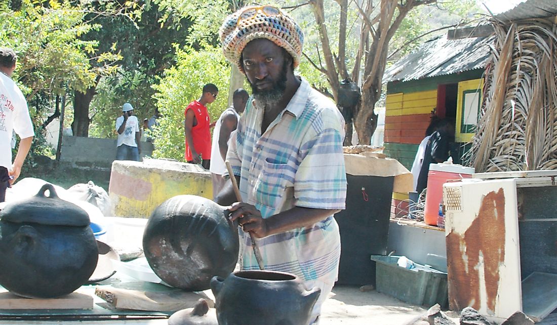 Man prepares food outdoors in pots in Bequia, St. Vincent And The Grenadines. Editorial credit: rj lerich / Shutterstock.com