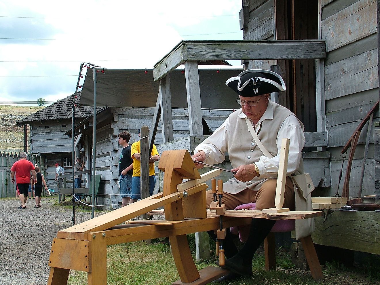 Craftsman in historical clothing sharpens a blade on a foot-powered whetstone at Old Fort Steuben, in Steubenville, Ohio.