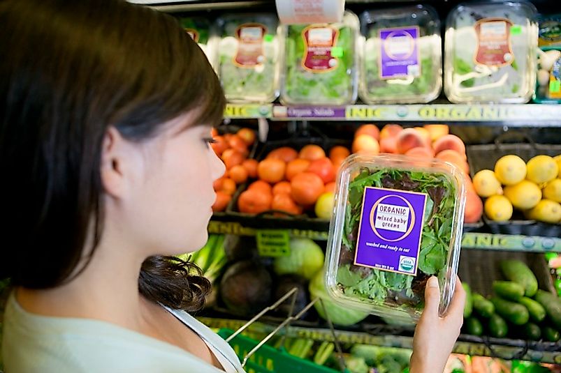 A discerning shopper debates spending a little extra money to opt for organic produce at the market.