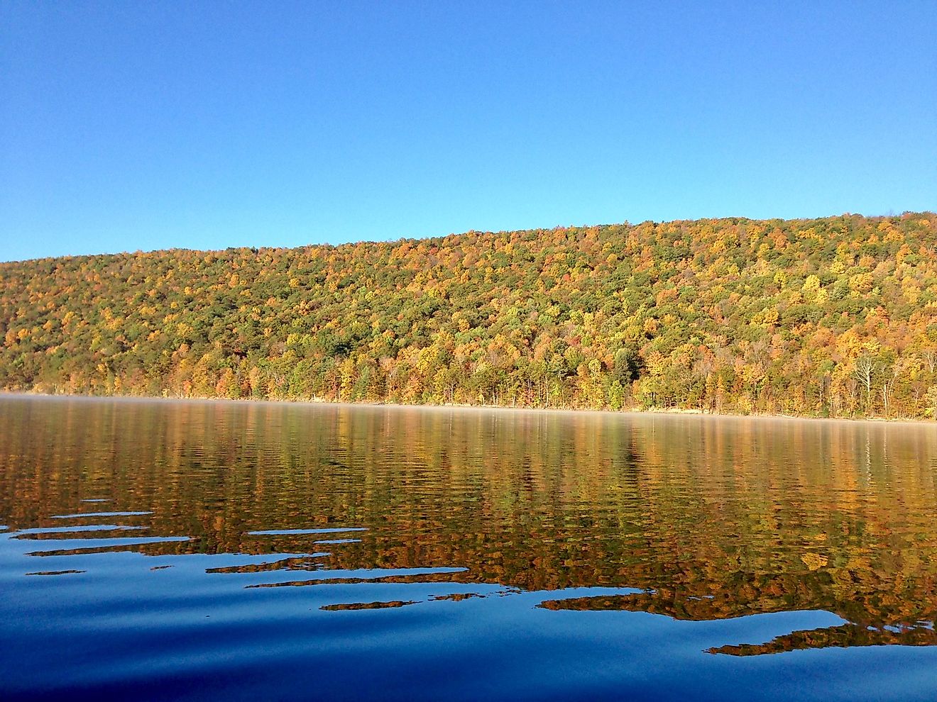 The clear, still waters of the Canadice Lake in New York, during autumn. 