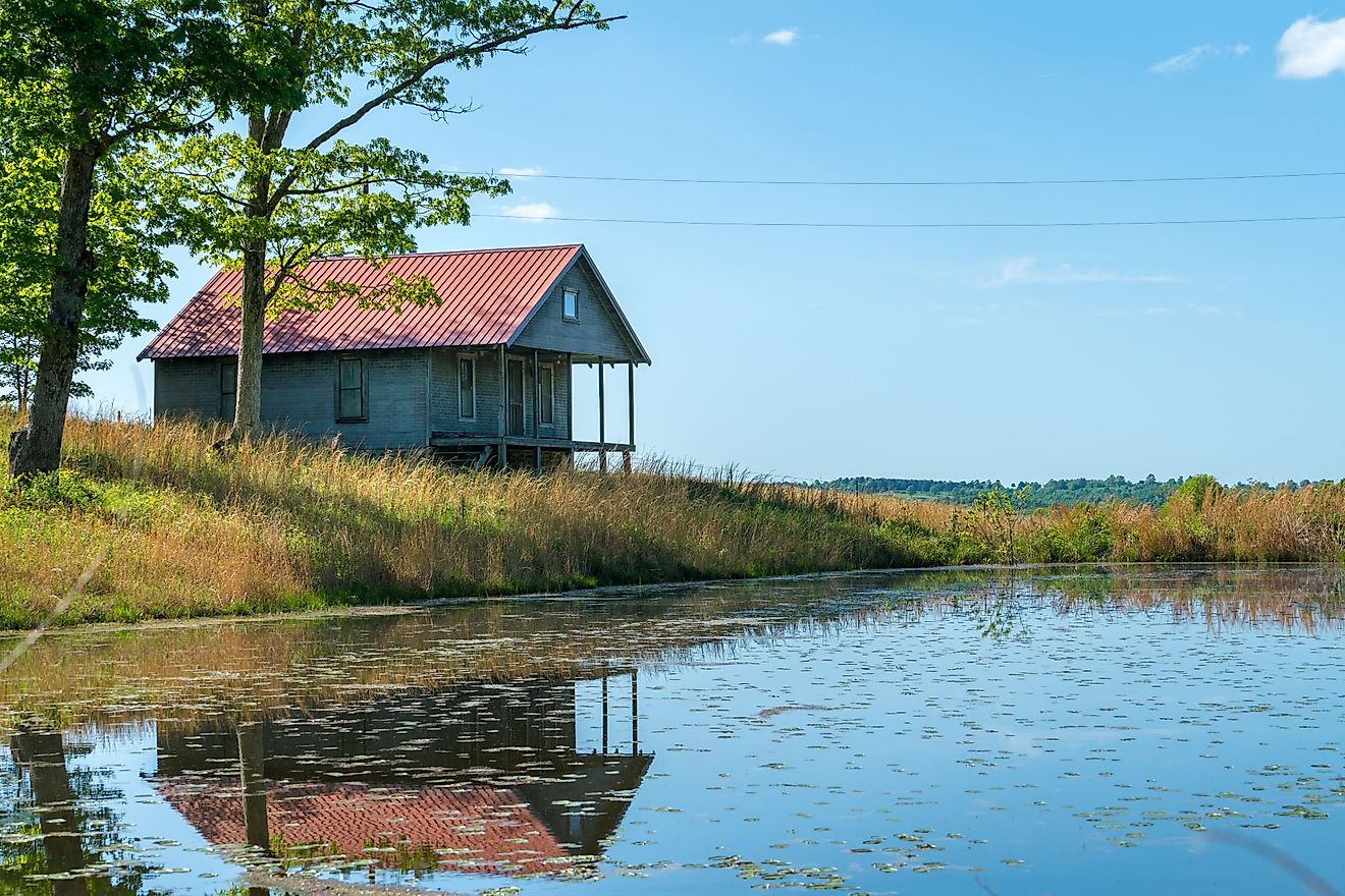 Rural old house barn reflected in pond water in northwest Arkansas, Ozark Mountains. 