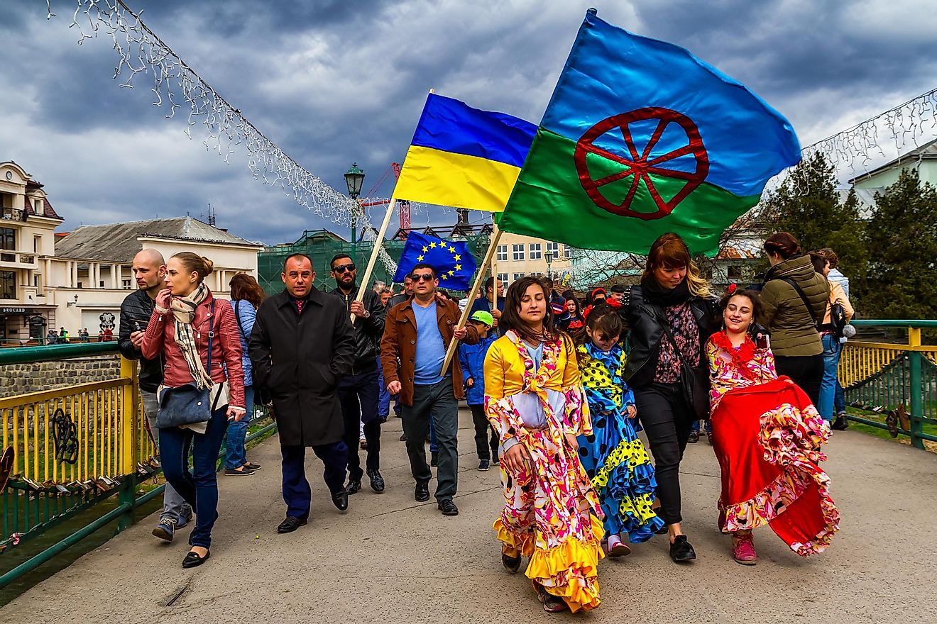 A festive procession of participants of the celebration of the International Roma Day in the city center of Uzhhorod, Ukraine. The flag at the front is the flag of the Romani people. Editorial credit: Yanosh Nemesh / Shutterstock.com