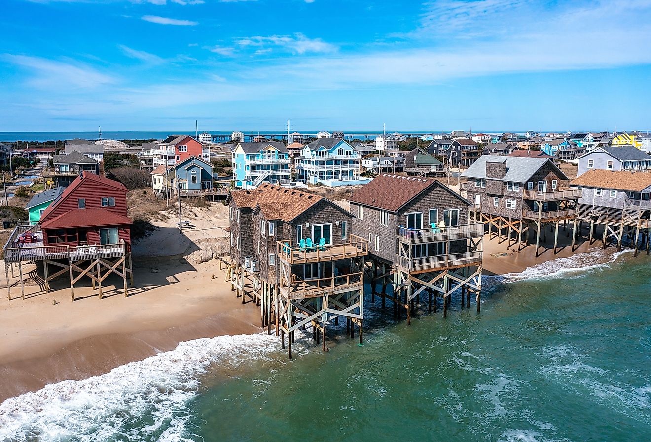 Aerial view of beach homes in Rodanthe North Carolina with pilings in the water at high tide on a sunny day.