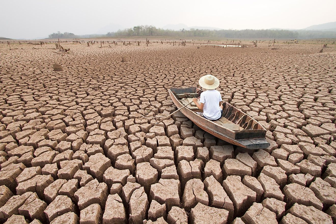 A man in a boat in a drought hit landscape.