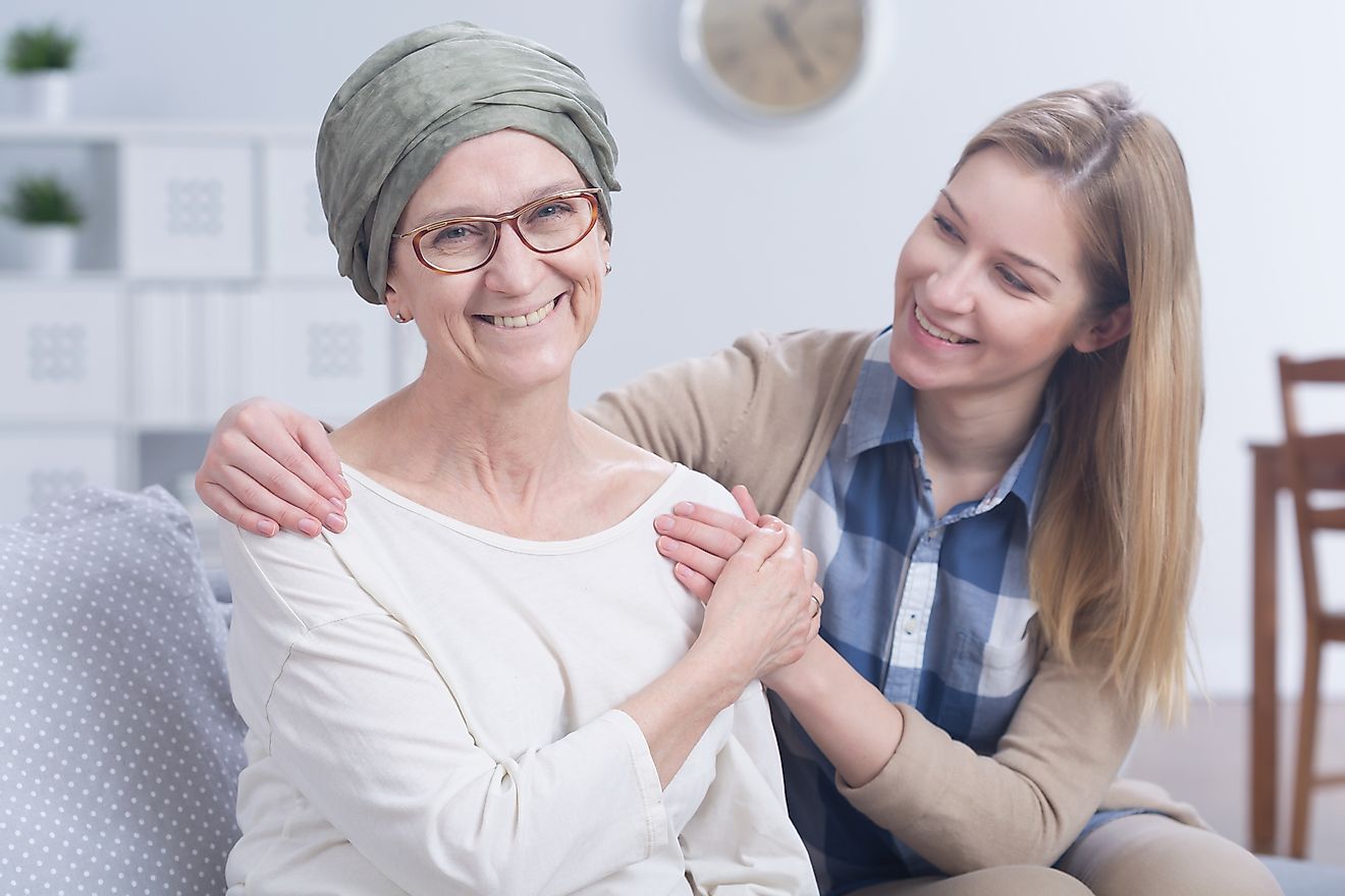 A smiling elderly cancer patient embraced by a young woman. Image credit: Photographee.eu/Shutterstock.com