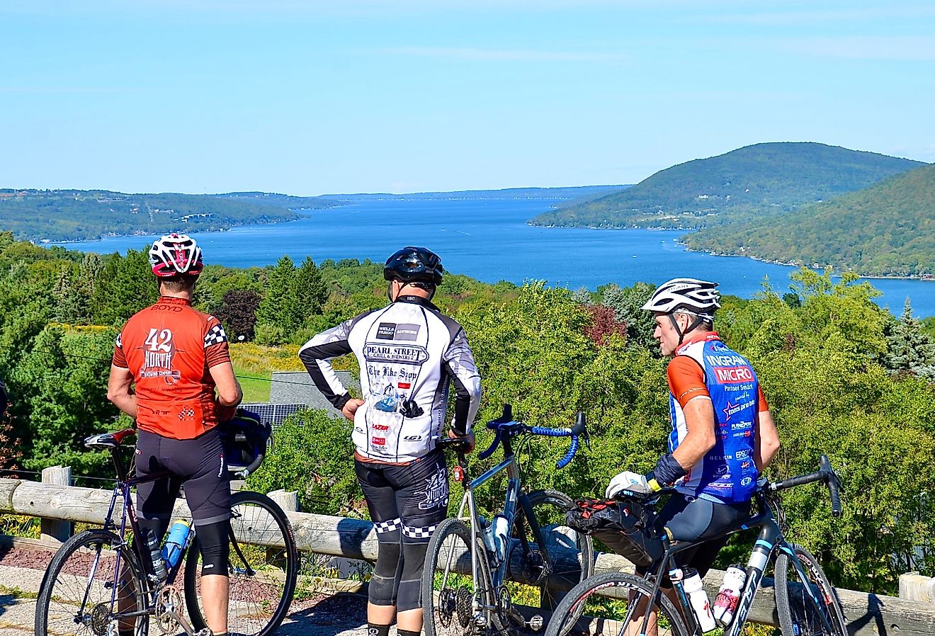 Bicyclists stop on route around Canandaigua Lake, New York with mountains in the background.