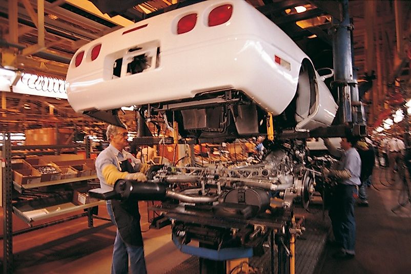 Automotive manufacturing workers building a car on an assembly line.