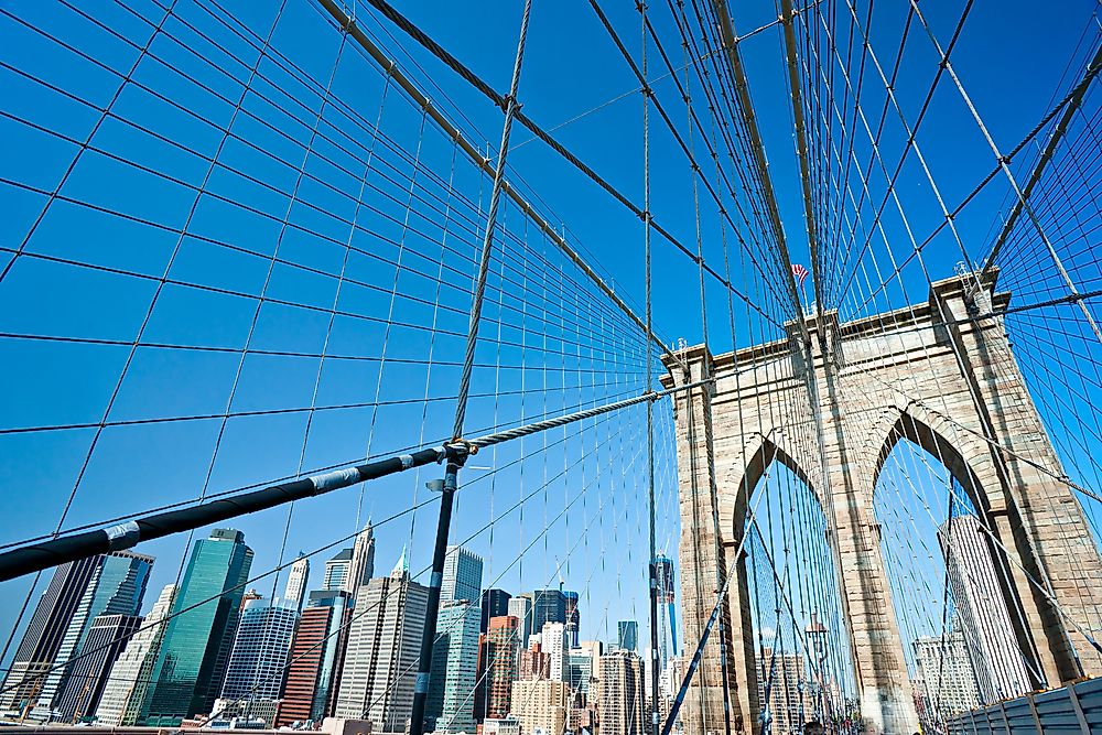 The buildings of New York peak out behind the Brooklyn Bridge.
