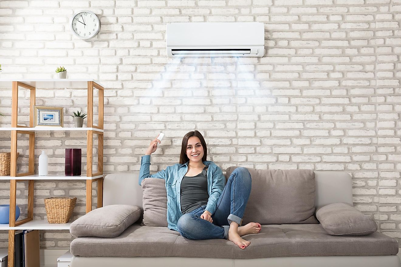 Woman Holding Remote Control Relaxing Under The Air Conditioner.