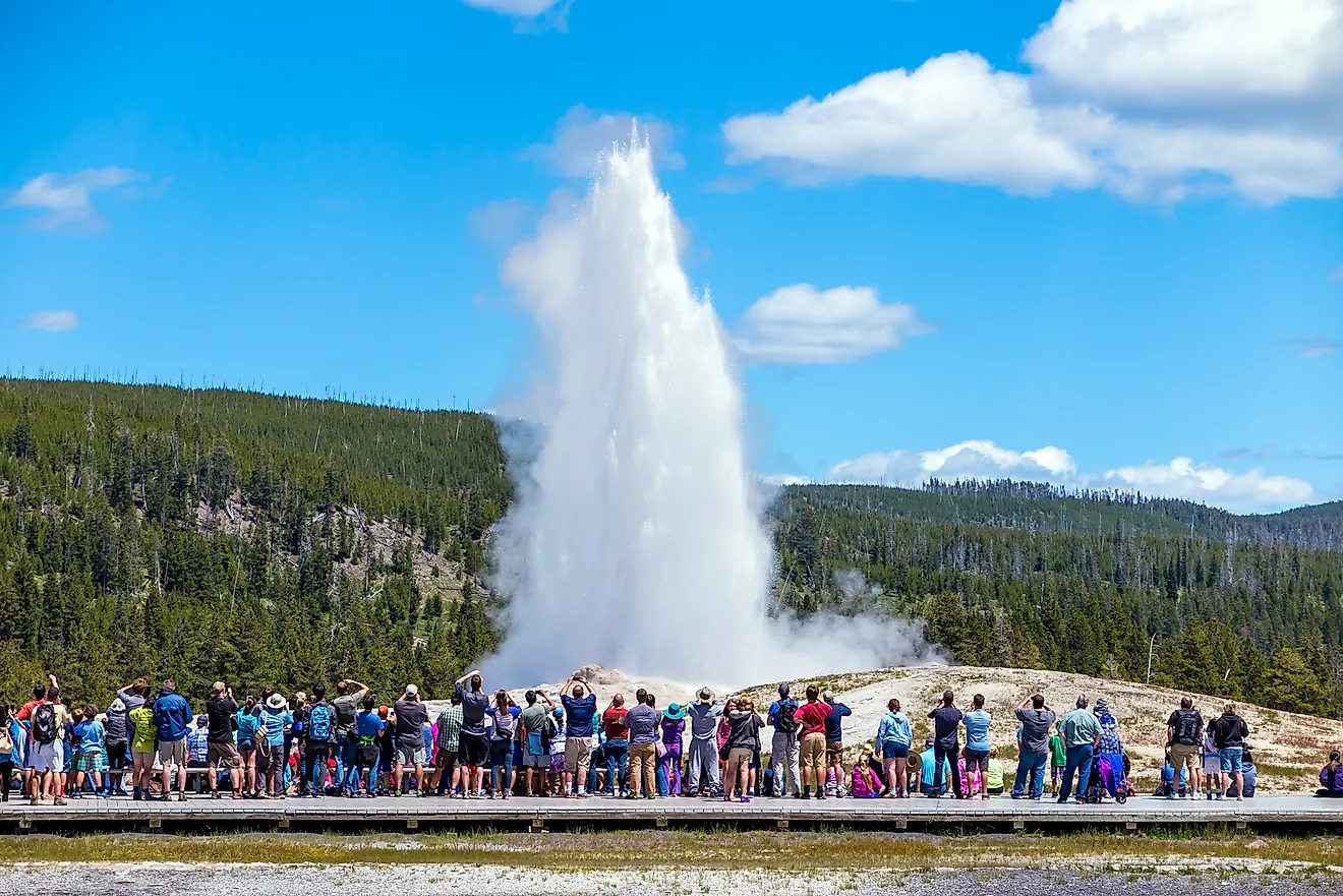 Tourists watching the Old Faithful erupting in Yellowstone National Park, US