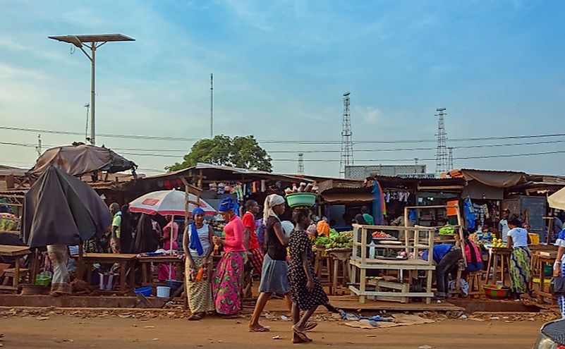 Street scene with the buyers, vendors selling their goods in a street market in the outskirt of Conakry city.
