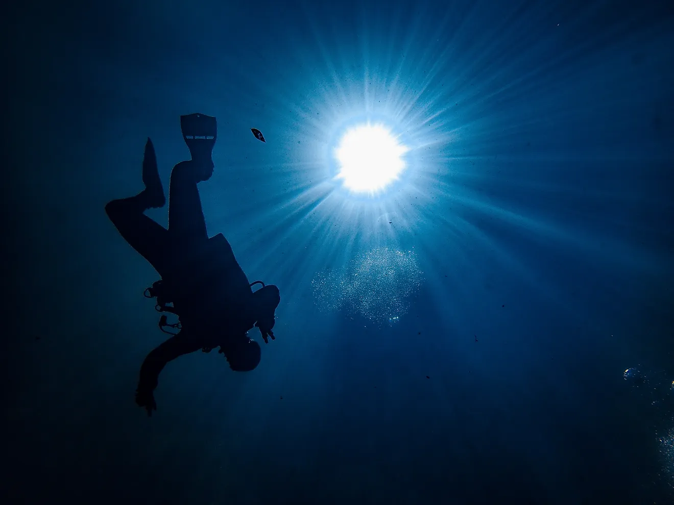 Underwater POV of sunburst with scuba diver in a blue hole, similar to what it would look like in the Green Banana. 