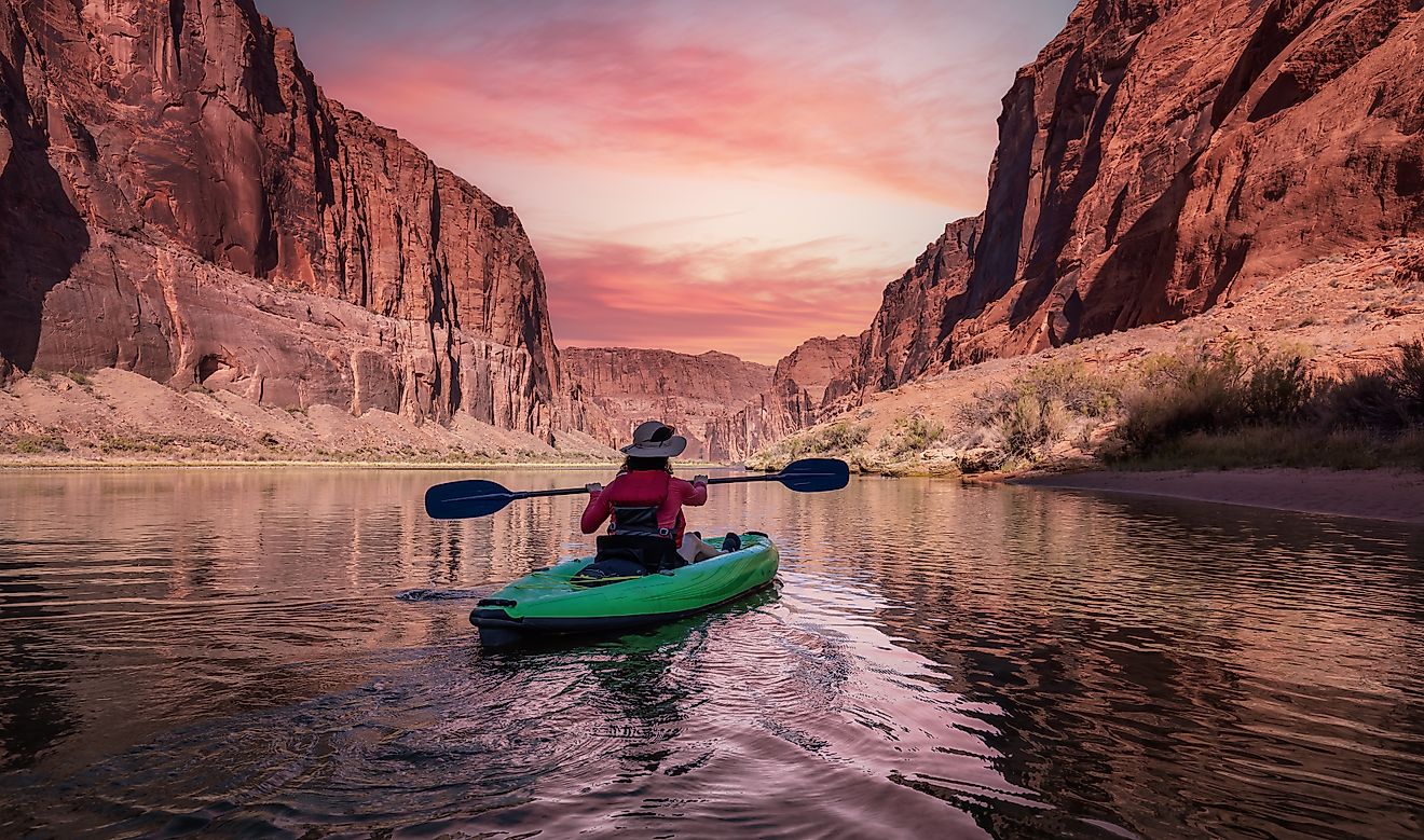 Glen Canyon, Arizona: Adventurous woman on a kayak paddling in the Colorado River during sunrise.