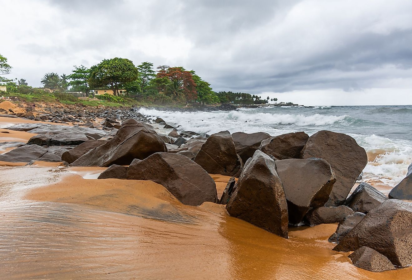 Beach with red sand and red rocks with a dramatic sky in Congo Town, Monrovia, Liberia. Image credit Dan_Manila