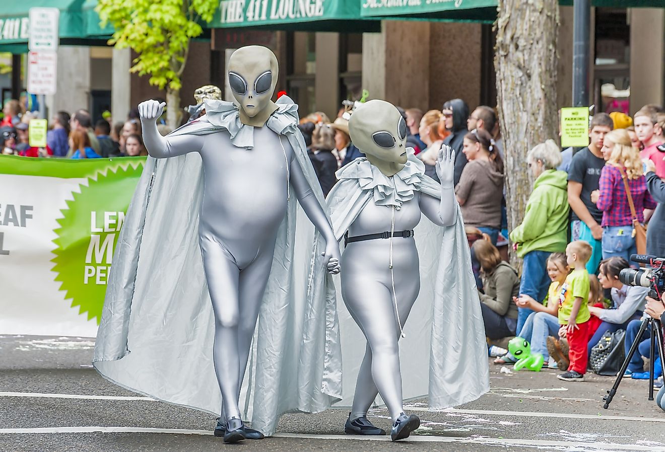A couple wearing silver alien costumes walk down the street in McMinnville, Oregon. Image credit Dee Browning via Shutterstock