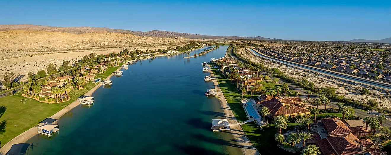 Aerial view of a private lake with waterfront homes and boat docks in a gated Coachella Valley community