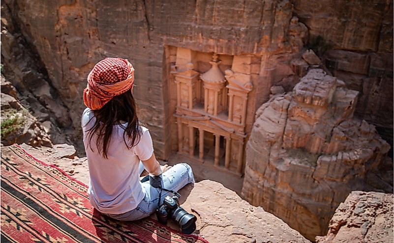 A traveler enjoying the stunning view of Petra's rock carvings from a viewpoint.
