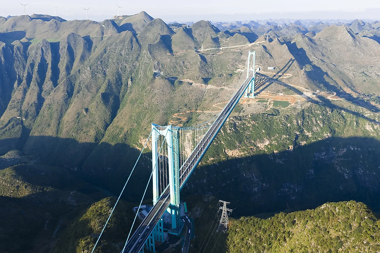 Aerial view of the Beipanjiang Bridge spanning the Huajiang Canyon in Guizhou, China. World's highest bridge structure crossing dramatic mountainous terrain with lush vegetation.