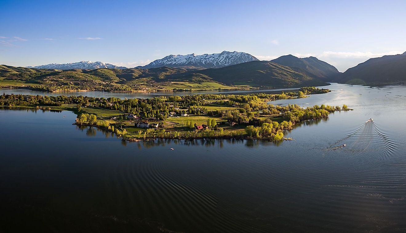 Aerial wide panorama view of Pineview Reservoir in Northern Utah with boats and the Wasatch Mountains on a blue sky day. 