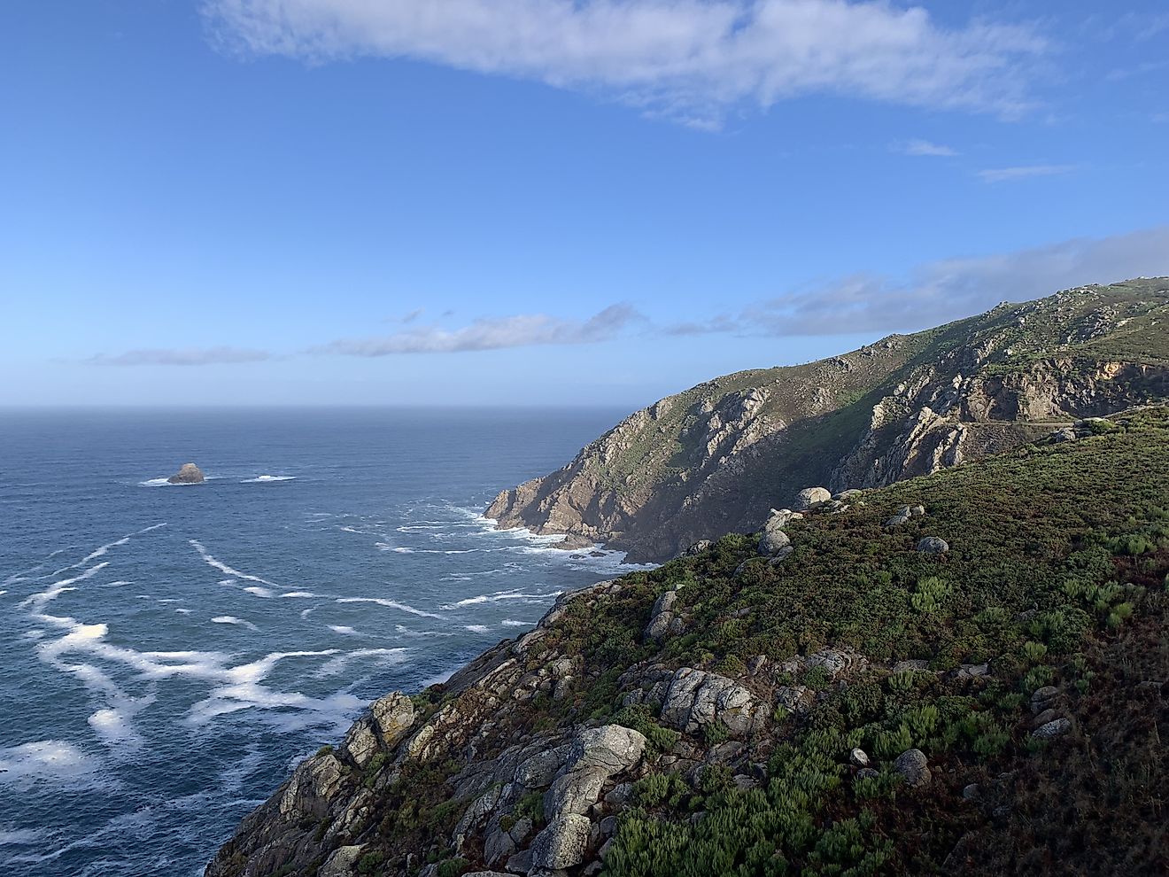 The blue expanse of the North Atlantic Ocean meets the steep cliffs of Cape Finisterre on the West Coast of Spain.