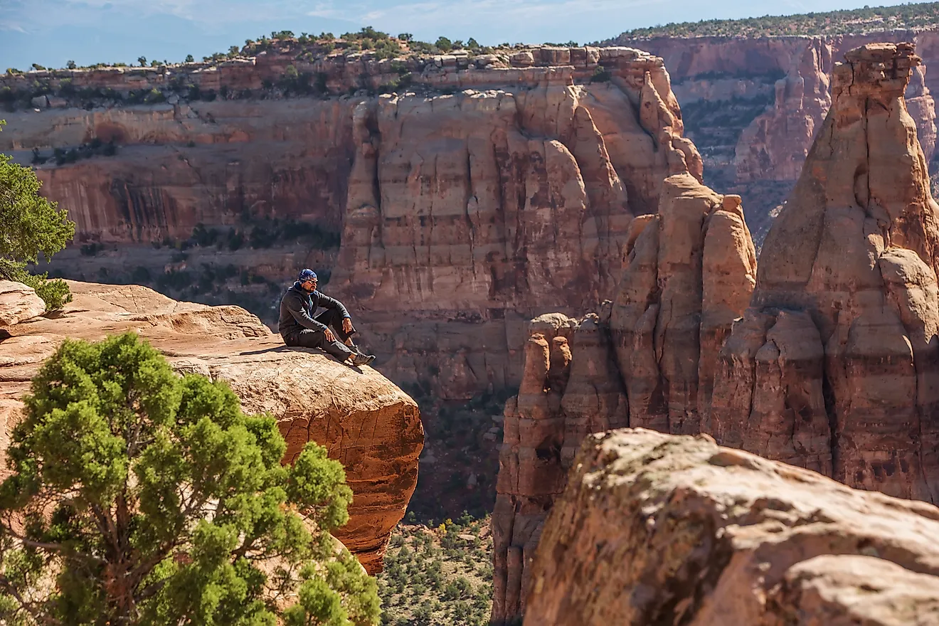 A hiker is sitting on a cliff in the Colorado National Monument area in Colorado.