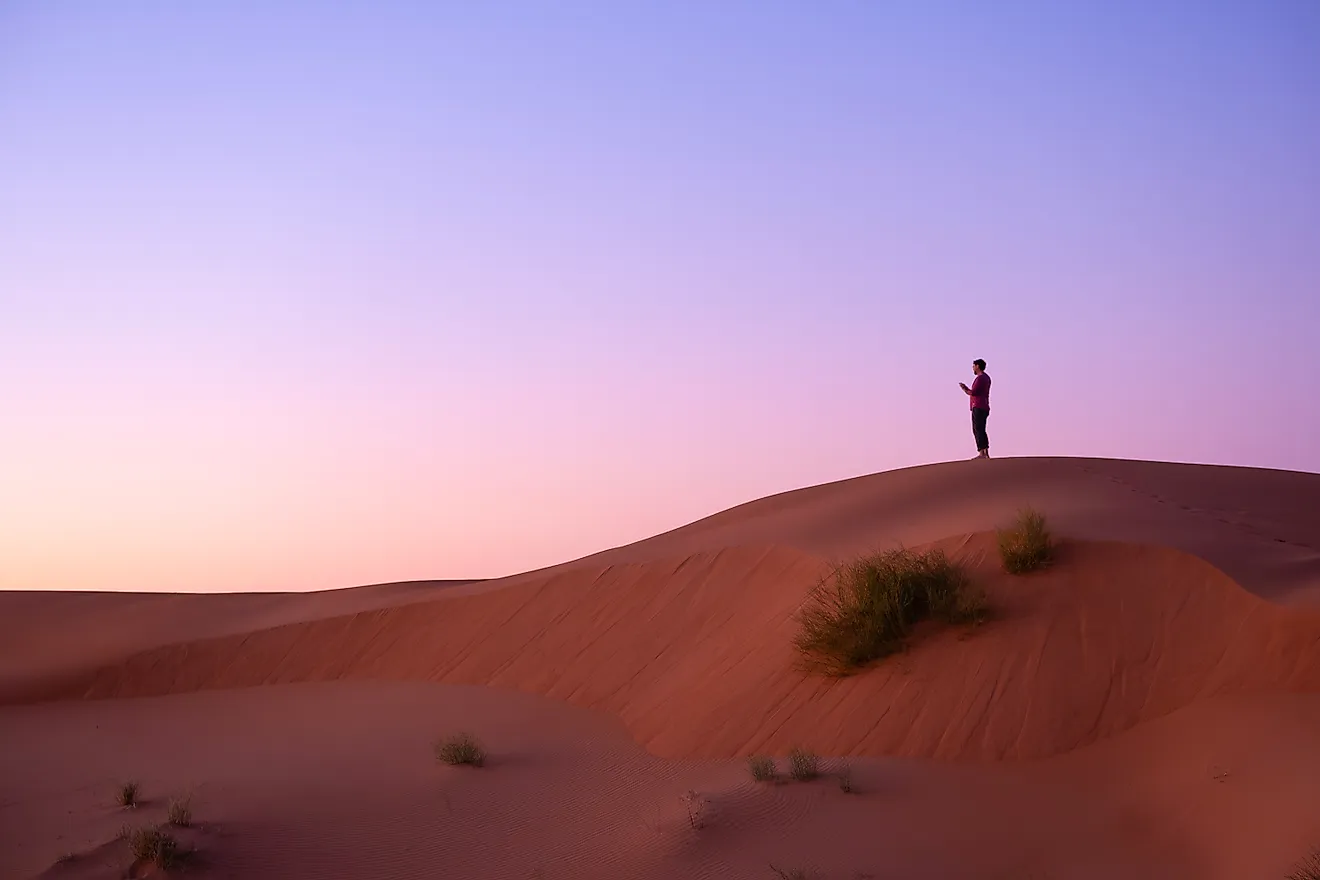Lone man using mobile phone in the desert. Via Shutterstock / Javier Ruiz