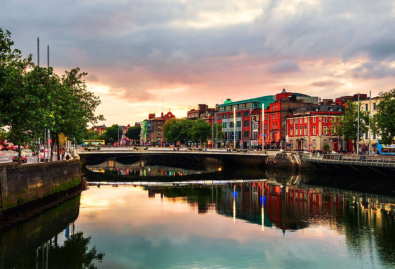 Embankment of Liffey River in Dublin, Ireland. Sunset view with buildings and city lights at the background. Image credit Madrugada Verde via Shutterstock.