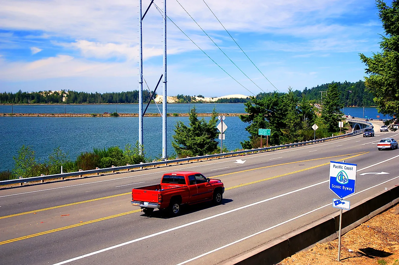 Car drives on Highway 101 with a Pacific Coast Scenic Byway sign in the foreground, Editorial credit: Karin Hildebrand Lau / Shutterstock.com