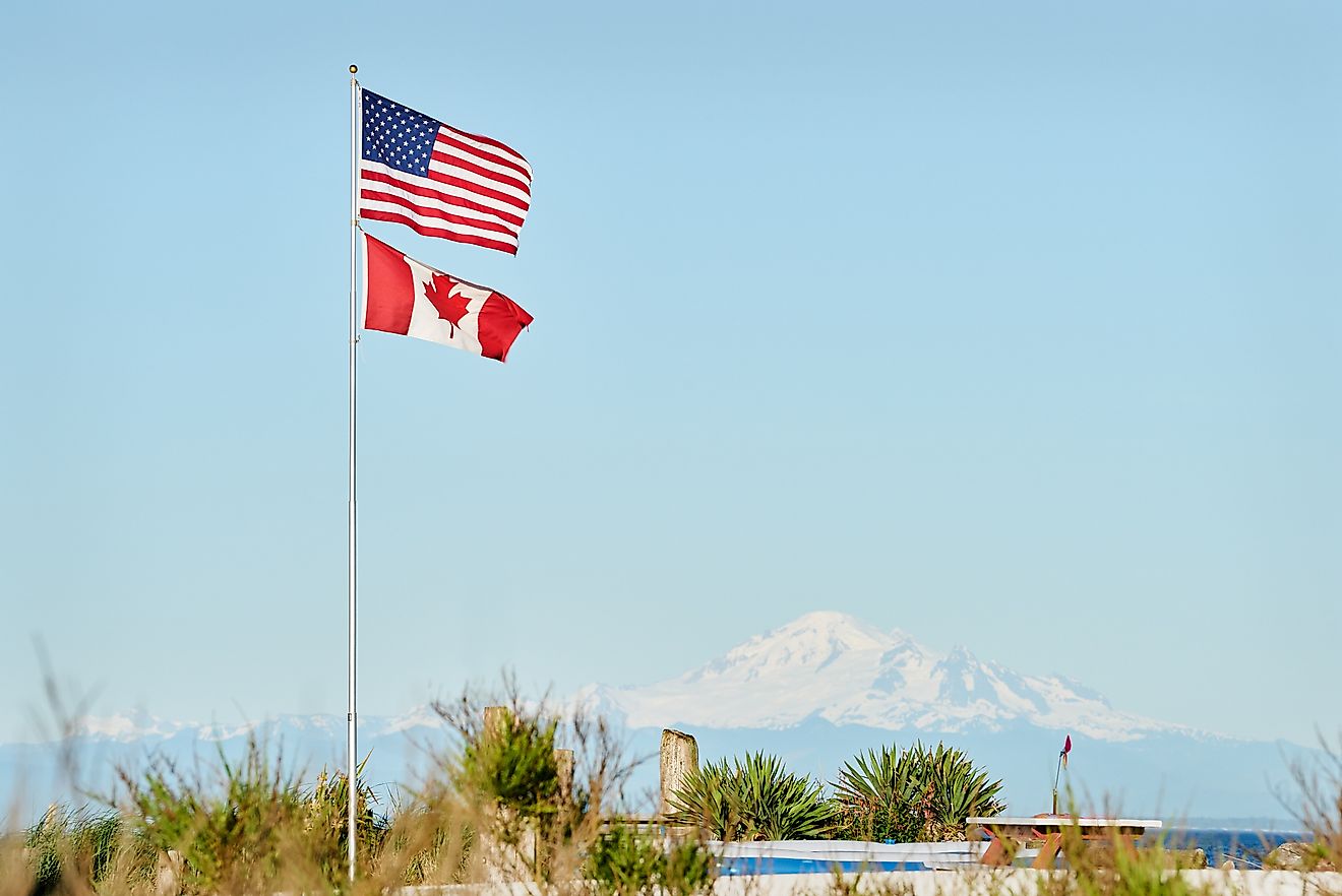 US and Canadian Flag. US and Canadian Flags fly in Point Roberts, Washington State. Mt Baker in the background. (Credit: Max Lindenthaler / Shutterstock)                                 