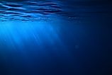 Underwater view of the ocean with rays of sunlight filtering through blue water