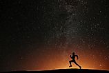 Runner athlete running on the hill with beautiful starry night background.